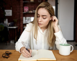 An attractive blonde student girl in a white blouse doing homework